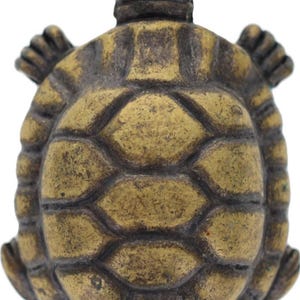 May include: A detailed, antique-style turtle figurine. The sculpture is a golden-bronze color with dark brown accents, showcasing a textured shell and detailed limbs. The turtle's head is raised, and its limbs are extended.
