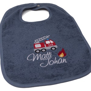 Op de afbeelding: Een blauwe badstof baby-slabbetje met een rode brandweerwagen en de naam "Matti Johan" geborduurd.