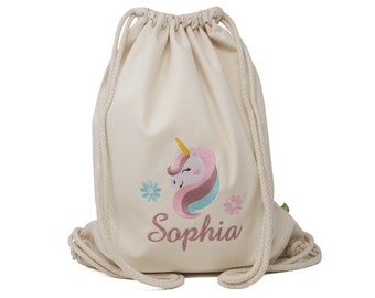 Könnte beinhalten: Eine weiße Kordeltasche mit einem pinkfarbenen und blauen Einhorn-Design und dem Namen "Sophia", der auf der Vorderseite gestickt ist.