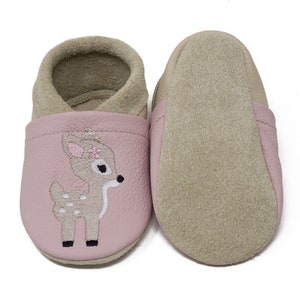 Pode incluir: Sapatos de beb&eacute; de couro rosa com um veado marrom bordado na frente. Os sapatos t&ecirc;m um forro de camur&ccedil;a e uma sola macia.