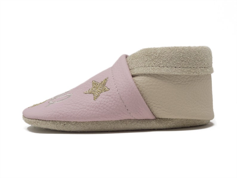 Pode incluir: Sapatos de beb&eacute; de couro rosa com acabamento em camur&ccedil;a bege e estrelas douradas com glitter.