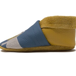 May include: Blue and yellow leather baby booties with a gray and white pattern on the toe.