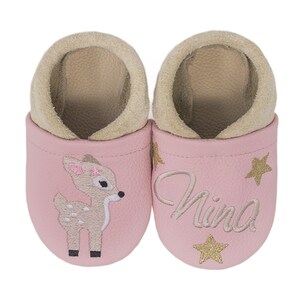 Pode incluir: Sapatos de beb&eacute; de couro rosa com um veado e estrelas douradas bordadas. Os sapatos dizem "Nina" em um deles.