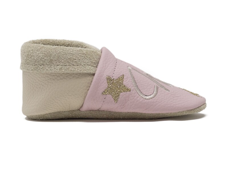 Pode incluir: Sapatos de beb&eacute; de couro rosa com uma estrela dourada e um design bordado. Os sapatos t&ecirc;m um forro bege macio.