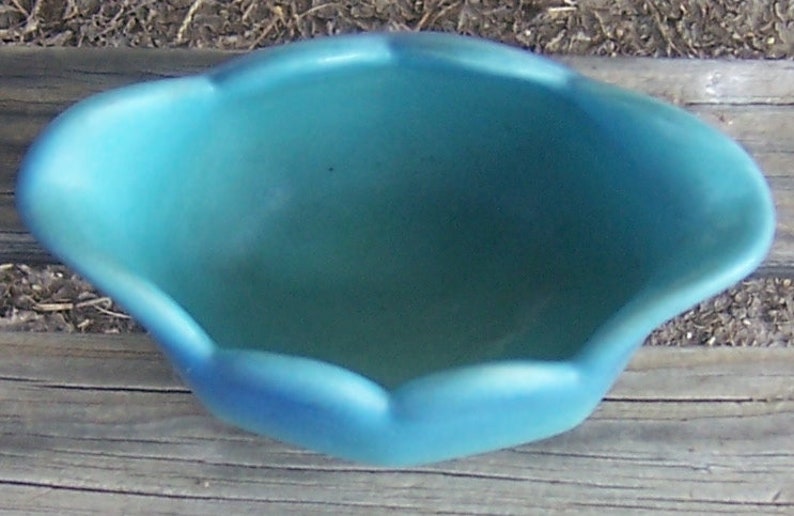 K&ouml;nnte beinhalten: Eine tealblaue Keramikschale mit einem gewellten Rand. Die Schale ist leer und hat eine glatte, gl&auml;nzende Oberfl&auml;che.