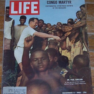 May include: A black and white magazine cover with the word "LIFE" in red letters. The cover features a photo of a man in a white shirt reaching out to a group of children. The text on the cover reads "CONGO MARTYR" and "DR. PAUL CARLSON". The date on the cover is "DECEMBER 4, 1964".