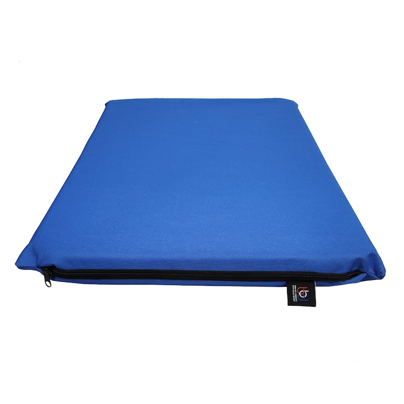 May include: A rectangular blue cushion with a black zipper closure along one edge. A small black tag with white text is attached to the cushion. The cushion is made of a solid blue fabric.