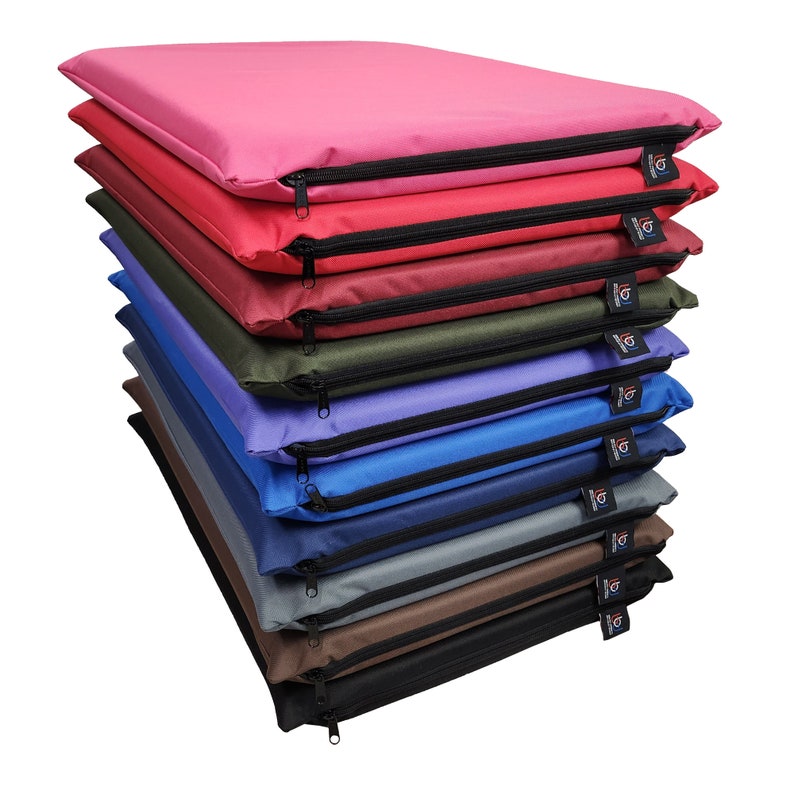 May include: A stack of colorful, rectangular cushions in various shades including pink, red, green, blue, and brown. Each cushion has a black zipper and a small tag. The cushions appear to be made of a durable, water-resistant material.