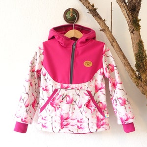 Könnte beinhalten: Eine rosa-weiße Kapuzenjacke mit Blumendruck. Die Jacke hat einen Reißverschluss und eine Kängurutasche. Die Jacke hat ein kleines braunes Etikett mit dem Text "C&C" darauf.