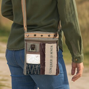 Könnte beinhalten: Crossbody-Tasche mit Patchwork-Design. Die Tasche hat eine Mischung aus Farben wie Olivgrün, Braun und Beige. Der Riemen hat ein Streifenmuster mit Sternakzenten. Der Text "CONQUERIR LE MONDE" ist sichtbar.