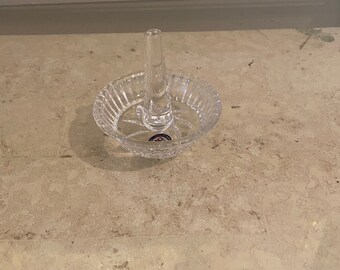 Op de afbeelding: Een glazen ringhouder van helder glas met een verhoogde middelste paal. De houder heeft een decoratief, geslepen glasontwerp.