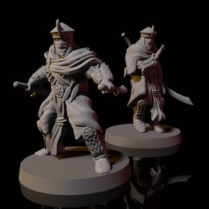 Puede incluir: Dos figuras en miniatura de guerreros que llevan capas con capucha y sostienen armas. Las figuras están pintadas de gris y se colocan sobre bases circulares.