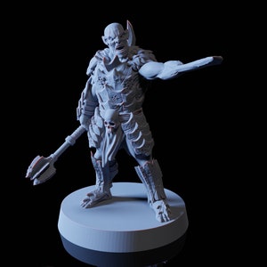 Op de afbeelding: Een grijs plastic miniatuurfiguur van een ork-krijger die een wapen vasthoudt. De ork draagt ​​een harnas en heeft een woeste uitdrukking.