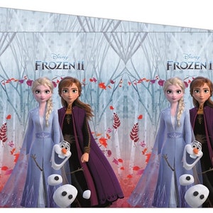 May include: Two Disney Frozen II characters, Elsa and Anna, stand in a snowy forest with Olaf the snowman. Elsa is wearing a light blue dress and Anna is wearing a dark purple dress. The text "Disney Frozen II" is at the top of the image.