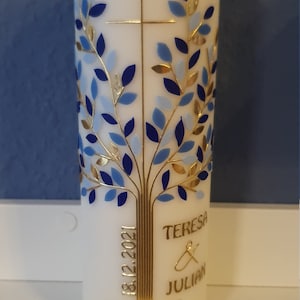 Könnte beinhalten: Weiße Kerze mit einem goldenen Baumdesign und blauen Blättern. Die Kerze trägt das Datum "18.12.2021" und die Namen "TERESA & JULIAN" in Gold.