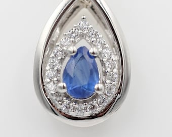 May include: A silver pendant necklace with a teardrop-shaped blue gemstone surrounded by a halo of smaller clear gemstones.