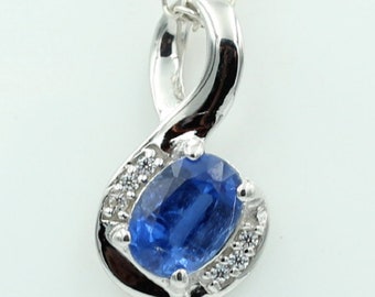 May include: A silver necklace with a blue gemstone pendant. The pendant is set in a silver infinity symbol design with small clear gemstones around the blue gemstone.