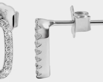 May include: A pair of silver stud earrings. Each earring features an oval design encrusted with small, clear gemstones. The earrings have a post and butterfly backing for secure wear. The design is simple and elegant.
