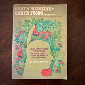May include: A yellow book cover with a green, red, and orange illustration of plants and flowers. The title of the book is "Earth Medicine-Earth Foods" and the subtitle is "Plant Remedies, Drugs, and Natural Foods of the North American Indians". The author is Michael A. Weiner. The book cover also includes the text "A guide to the wild plants the Indians used for soups and salads, poultices and decoctions, tonics and sedatives." and "Over 140 Illustrations".