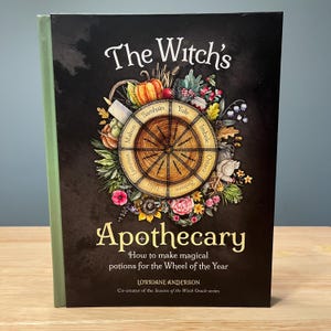 May include: A hardcover book titled The Witch's Apothecary: How to make magical potions for the Wheel of the Year by Lorriane Anderson. The black cover features a central wheel illustration with seasonal labels surrounded by colorful botanical art.