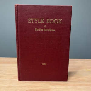 May include: A maroon hardcover book titled "STYLE BOOK of The New York Times" with gold lettering. The year "1950" is printed at the bottom. The book has a textured cover and is in good condition.