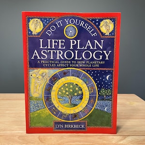 May include: A book titled Do It Yourself Life Plan Astrology by Lyn Birkbeck with a red border. The cover features a blue background with stars, a central yellow zodiac wheel, a tree, and an angel illustration. The text reads A Practical Guide to How Planetary Cycles Affect Your Whole Life.