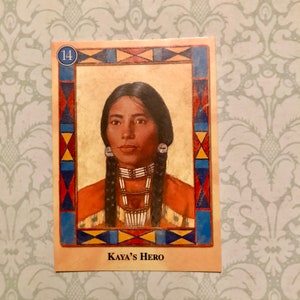 K&ouml;nnte beinhalten: Eine Sammelkarte mit dem Portr&auml;t einer indianischen Frau mit langen schwarzen Z&ouml;pfen. Die Karte ist mit der Nummer 14 versehen und tr&auml;gt den Text "Kaya's Hero" am unteren Rand.
