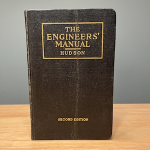 May include: A vintage, black hardcover book titled "THE ENGINEERS' MANUAL" by Hudson. The title and author's name are in gold lettering within a gold rectangular border. The words "SECOND EDITION" are at the bottom.