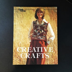 May include: A magazine cover featuring a woman wearing a brown and white patterned vest with a colorful patch on the front. The magazine is titled "Family Circle Creative Crafts".