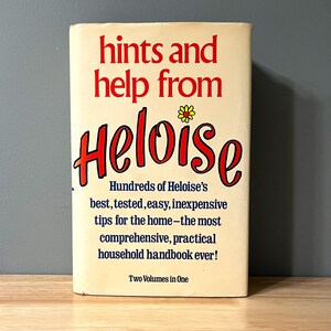 May include: A vintage book titled "hints and help from Heloise" with a yellow flower illustration. The book cover is cream with red and blue text. The book is a collection of household tips and tricks.
