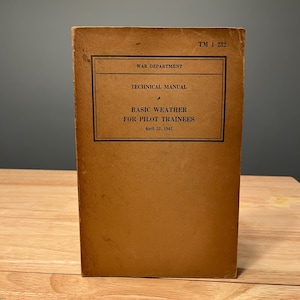 May include: A vintage technical manual titled "Basic Weather for Pilot Trainees" from the War Department. The cover is a faded brown with black text and a rectangular border. The manual's publication date is April 22, 1942.