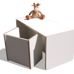May include: White children's table and chair set with a stuffed giraffe toy on top of the table.