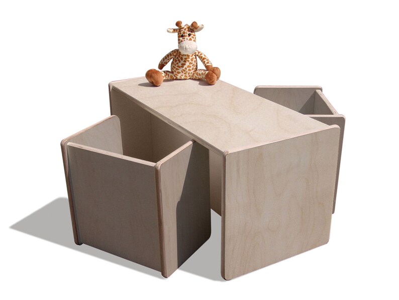 May include: A light wood children's table and four chairs with storage compartments. A stuffed giraffe toy sits on the table.