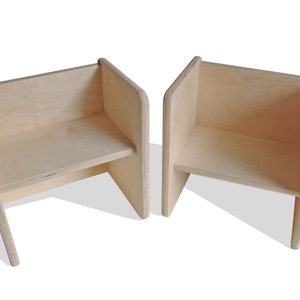 May include: Two wooden chairs with a simple, modern design. The chairs are made of light-colored wood and have a slightly angled back.