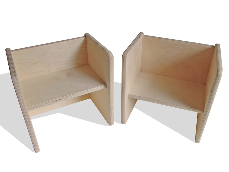 May include: Two wooden chairs with a simple, modern design. The chairs are made of light-colored wood and have a slightly angled back.