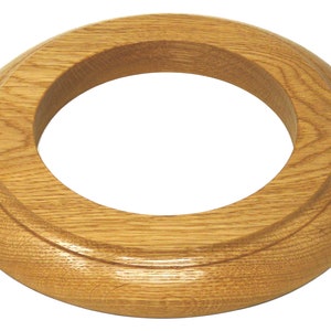 May include: A wooden ring with a smooth, rounded surface. The ring is made of light brown wood and has a natural grain pattern.