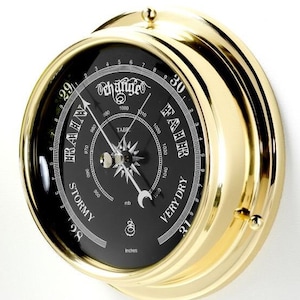 May include: A brass barometer with a black face and a white needle. The face has a scale for measuring air pressure in inches and millibars. The scale is marked with the words "Very Dry" and "Stormy".