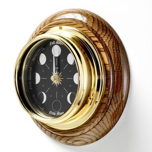 Può includere: Un orologio da parete in ottone e rovere con un quadrante nero e un quadrante delle fasi lunari. Il quadrante mostra le fasi lunari, dalla luna nuova alla luna piena.