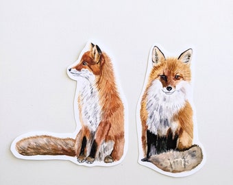 Pode incluir: Duas ilustrações de aquarela de raposas vermelhas. Uma raposa está sentada com a cabeça virada para o lado, enquanto a outra raposa está sentada com a cabeça voltada para a frente. Ambas as raposas têm acentos brancos no peito e na cauda.