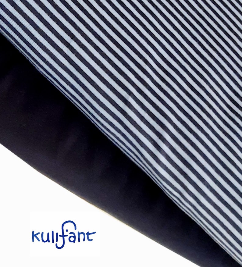 May include: Two layers of fabric are shown, one with a pattern of thin vertical black and white stripes and the other a solid dark black colour. The blue text kulifant is printed in the lower left corner of the image on a white background.