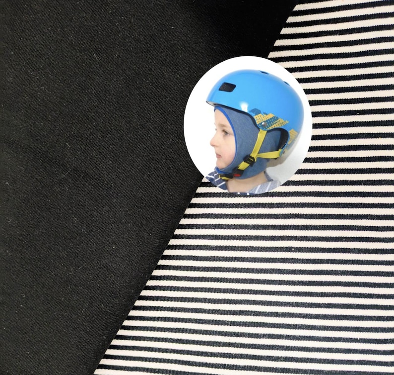 May include: A fabric swatch featuring a solid black section alongside a section with thin horizontal black and white stripes. A circular inset shows a blue helmet with yellow straps worn over a blue fabric head covering by a person in profile.