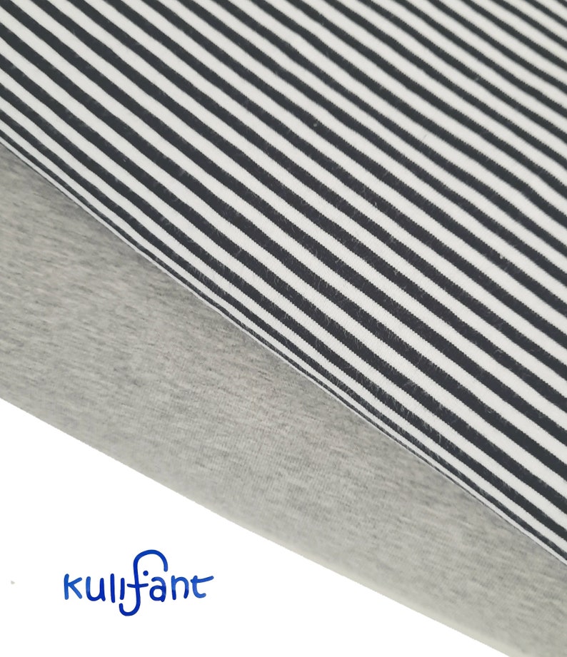 May include: Two folded pieces of fabric stacked together. The top layer features a pattern of thin black and white vertical stripes. The bottom layer is a solid heather grey colour. The blue text kulifant is printed in the bottom left corner.