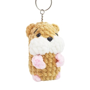 May include: A brown and white crocheted hamster keychain with pink paws and a silver key ring.