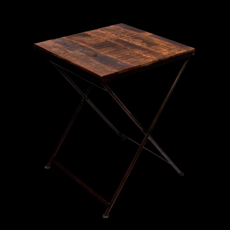 Peut inclure: Petite table d'appoint carr&eacute;e avec un plateau en bois brun fonc&eacute; et une base pliante en m&eacute;tal fonc&eacute;. Le plateau est fait de planches de bois et la base a un design en forme de X. La table mesure environ 61 cm de haut.