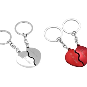 Può includere: Due portachiavi argentati con un design a forma di cuore spezzato. I cuori sono incisi con i nomi "Laura" e "Forever" e la data "21.05.1996".