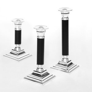 May include: Set of three silver candle holders with black bases. The candle holders are of varying heights and have square bases.