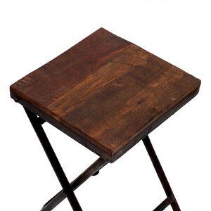 Peut inclure: Petite table pliante carr&eacute;e avec un plateau en bois brun fonc&eacute; et un cadre en m&eacute;tal fonc&eacute;. Le plateau de la table mesure environ 30 cm de c&ocirc;t&eacute;. Les pieds sont inclin&eacute;s et se croisent pour la stabilit&eacute;.