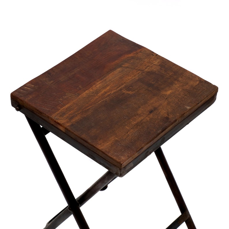 Peut inclure: Petite table pliante carr&eacute;e avec un plateau en bois brun fonc&eacute; et un cadre en m&eacute;tal fonc&eacute;. Le plateau de la table mesure environ 30 cm de c&ocirc;t&eacute;. Les pieds sont inclin&eacute;s et se croisent pour la stabilit&eacute;.