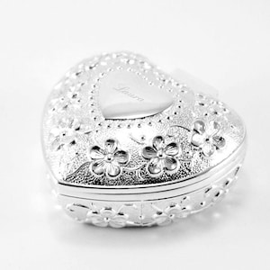 May include: Silver heart-shaped trinket box with an engraved floral design and the name "Laura" on the lid.