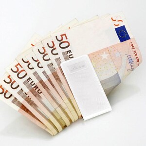 May include: A white money clip with the word "Luxury" printed on it, holding a stack of ten 50 euro bills.